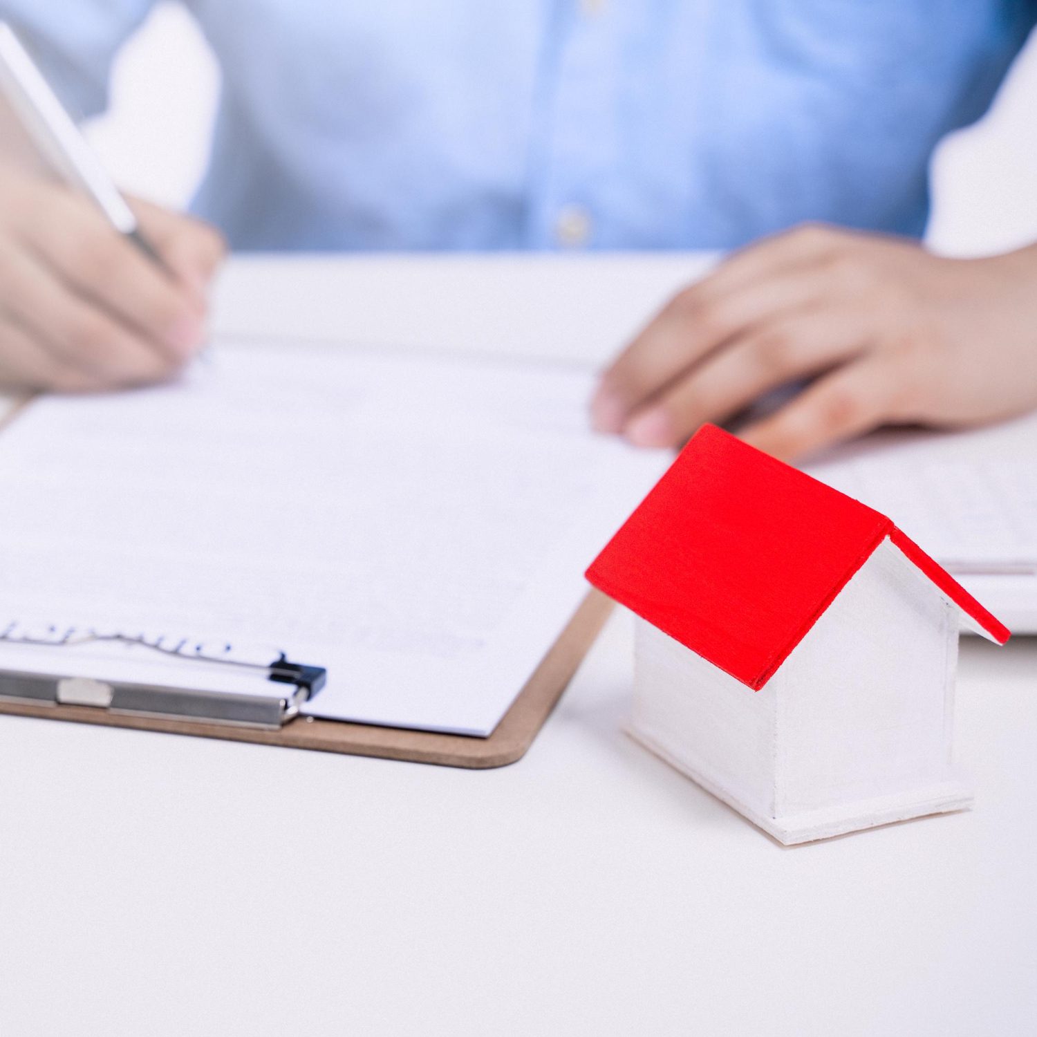 business-concept-young-asian-man-blue-shirt-calculates-signs-agreement-contract-buy-house-loan-payment-paying-insurance-tax-close-up closeup shot of a person writing in a book with a gavel on the table